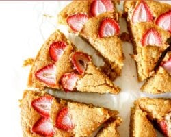 This is an overhead image of sliced strawberry lemon cake. The cake slices are slightly pulled apart and are sitting on a white piece of parchment paper. Text overlay reads "strawberry lemon cake."