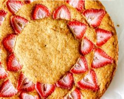 This is an overhead image of strawberry lemon cake. The cake sits on a white piece of parchment paper. Text overlay reads "strawberry lemon cake."