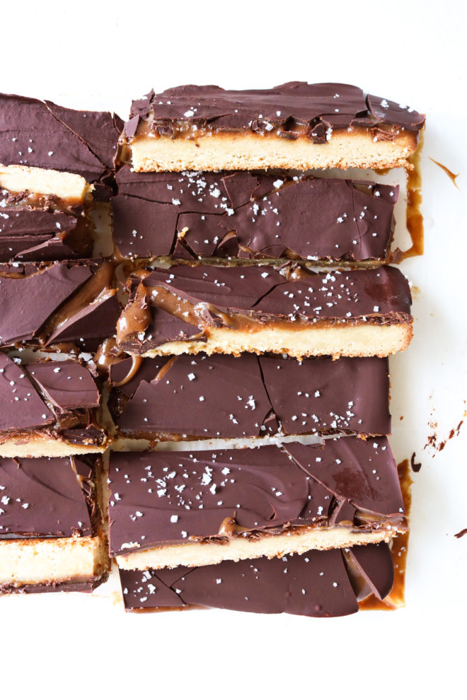 This is an overhead image of homemade twix bars. The bars are cut so show the shortbread cookie layer, the caramel layer and the chocolate topping.
