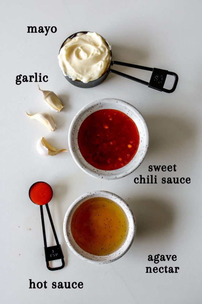 This is an overhead image of five ingredients to make bang bang sauce: mayonnaise, garlic, sweet chili sauce, hot sauce, and agave nectar. The ingredients sit on a white counter.