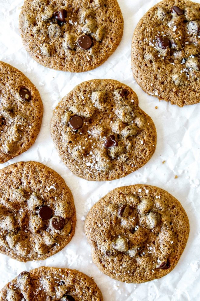 This is an overhead image of chocolate chip cookies on a white piece of parchment paper.