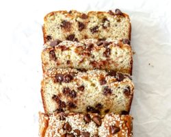 This is an overhead image of a chocolate chip tahini banana bread. Three slices are cut from the bread and are laying down on a white surface. Text overlay reads "chocolate chip tahini banana bread."