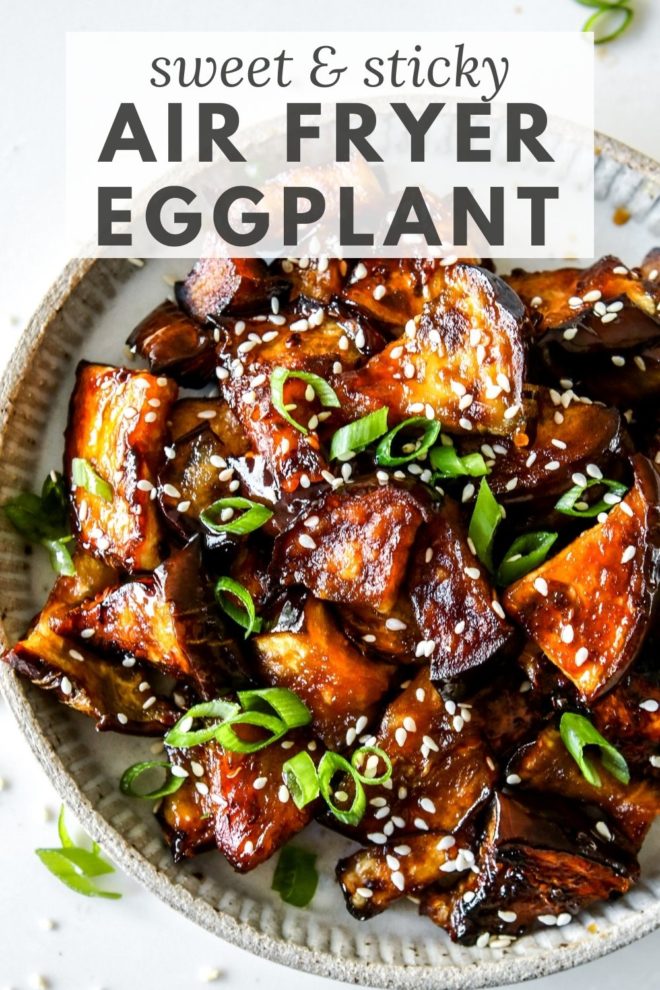 This is an overhead image of a plate with caramelized, glazed eggplant pieces. The eggplant has sesame seeds and scallions on it. The plate sits on a white counter. Text overlay reads "sweet & sticky air fryer eggplant."