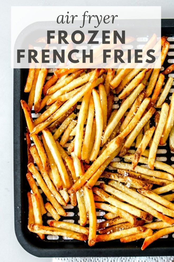 This is an overhead image of an air fryer tray with cooked french fries on it. The fries are sprinkled with salt. The tray is on a white paper towel and on a white counter. Text overlay reads "air fryer frozen french fries."