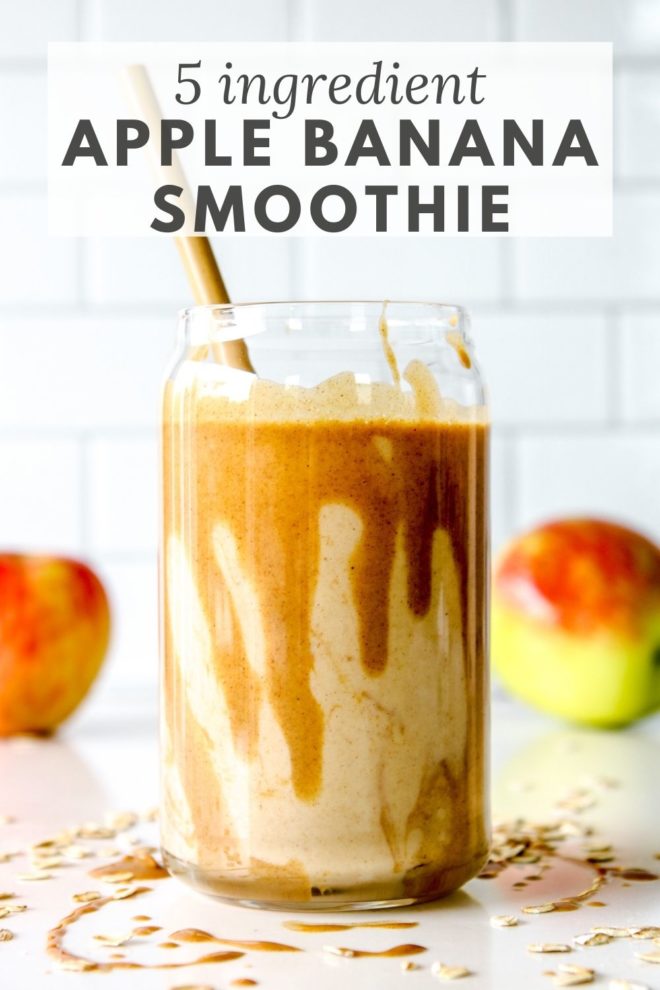 This is a side view of a glass with a smoothie and some peanut butter dripping inside the glass. The glass is sitting on a white counter with some peanut butter and oats. There are two apples blurred in the background. Text overlay reads "5 ingredient apple banana smoothie."