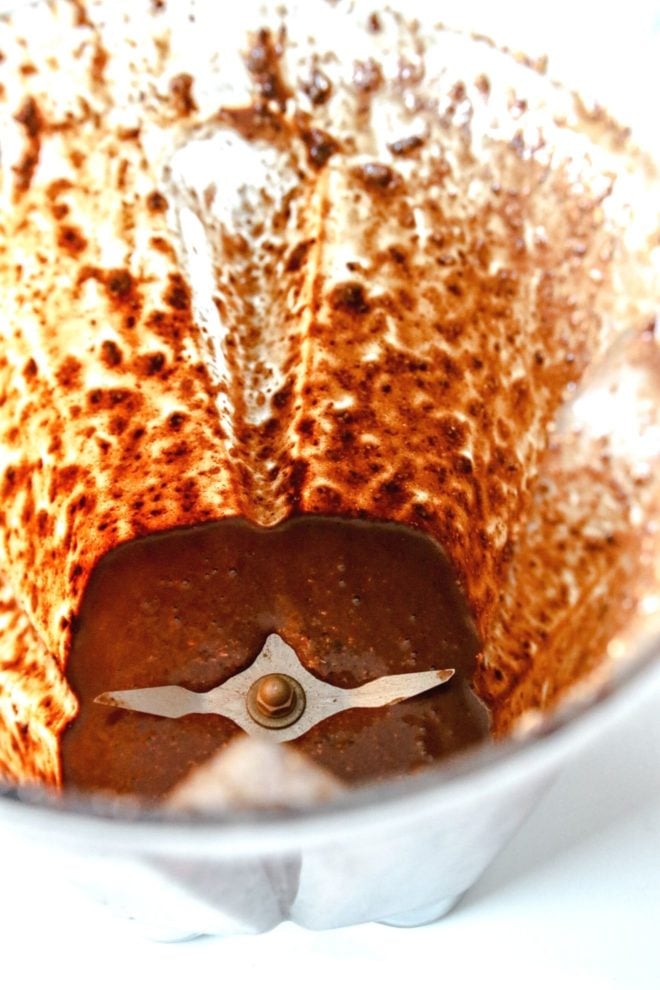 This is an image looking into a blender with a chocolate blended mixture. The blender sits on a white counter.