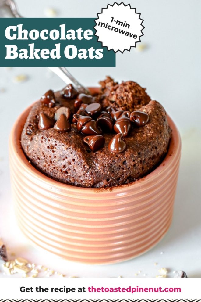 This is a side view looking at a light pink dish with chocolate baked oats inside. The baked oats are topped with melted chocolate chips and a spoon scooping out a bite. The dish sits on a white counter with oats scattered around. Text overlay reads "chocolate baked oats 1 min microwave."