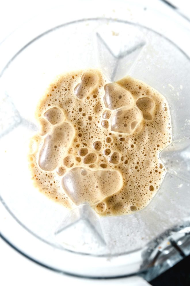 This is an overhead image of a blender with a pumpkin spice latte blended up and frothy. The blender sits on a white counter.