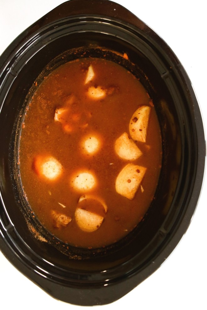 This is an overhead image of a slow cooker with pumpkin soup ingredients in it. The slow cooker sits on a white background.