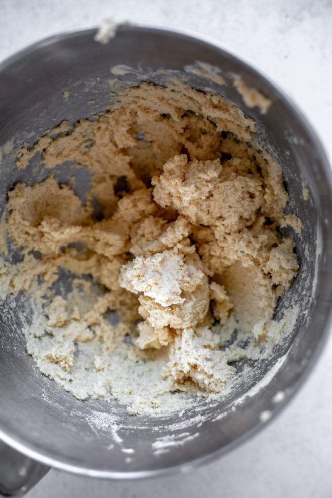 This is an overhead image of a silve mixture bowl with sugar cookie dough inside. The bowl sits on a white surface.