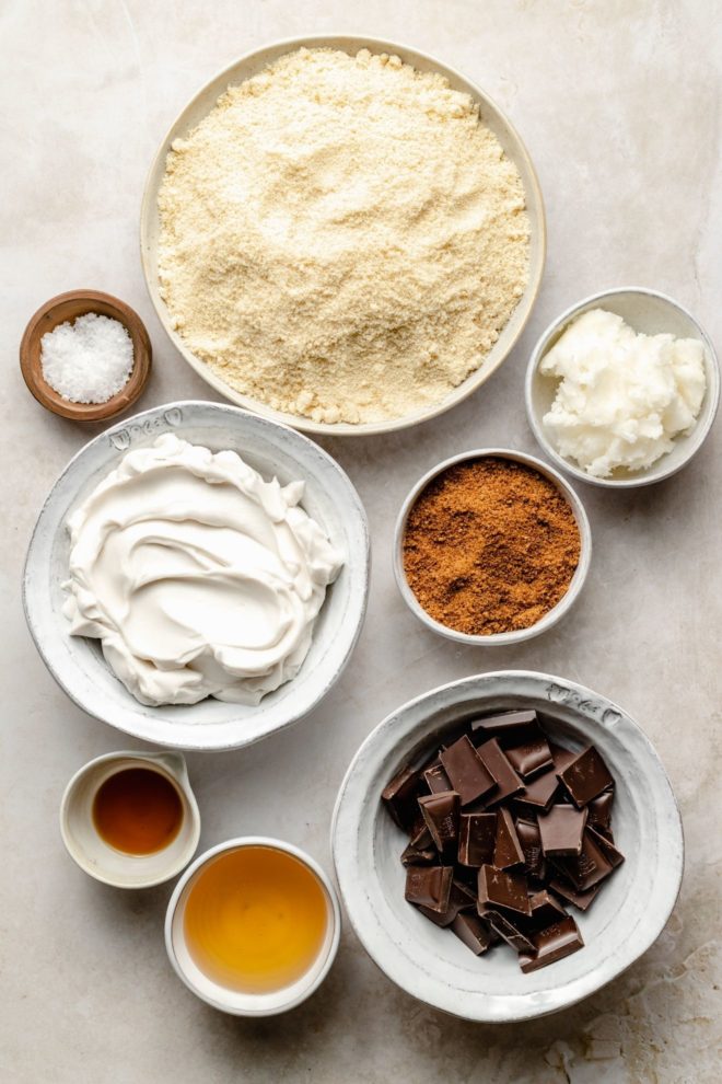 This is an overhead view of ingredients needed to make homemade vegan twix bars. The ingredients sit on a white counter.