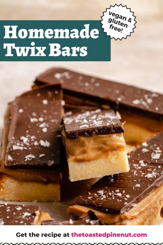This is a closeup of a twix bar with three layers: shortbread, caramel, and chocolate. The bar is leaning against the other bars. The bars sit on a white/beige surface. Text overlay reads "homemade twix bars vegan & gluten free!"