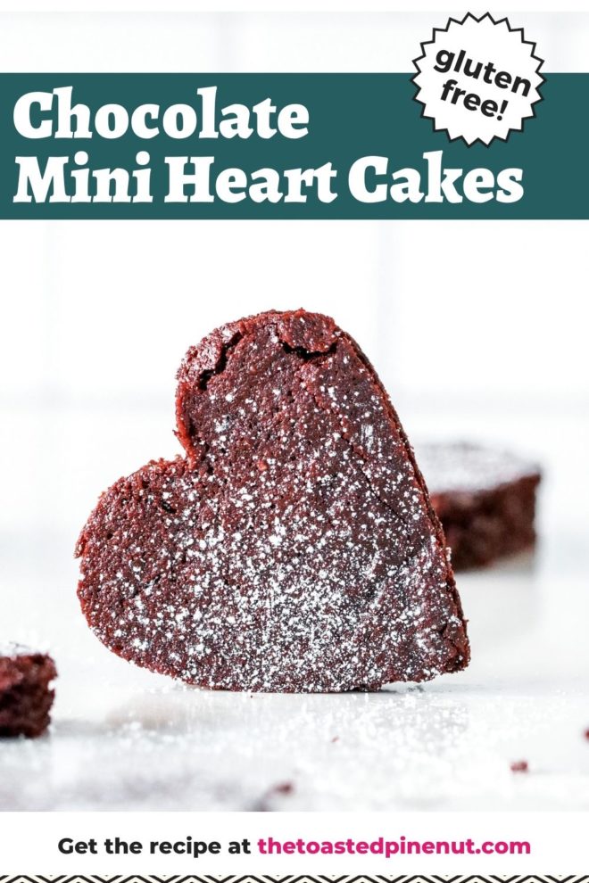 This is a side view of a chocolate heart cake leaning on its side. The cake is on a white counter with more chocolate heart cakes around it. The cakes are dusted with powdered sugar. Text overlay reads "chocolate mini heart cakes gluten free!"