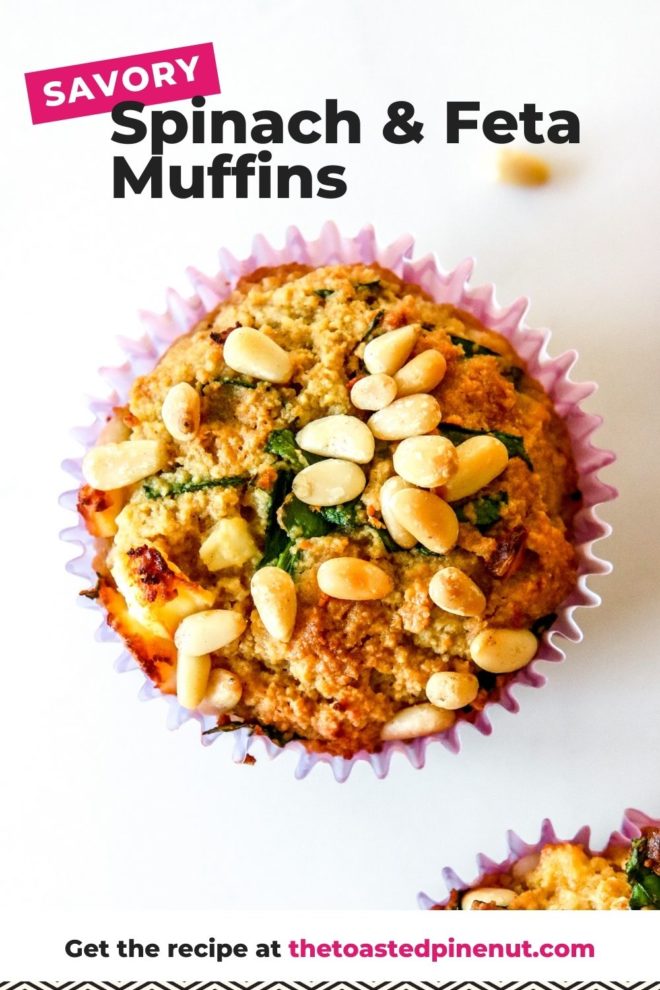 This is an overhead image of muffins with pine nuts and spinach. The muffin is lined with a purple paper liner and sits on a white counter with two other muffins to the right of the images and a couple pine nuts on the counter. Text overlay reads "savory spinach & feta muffins."