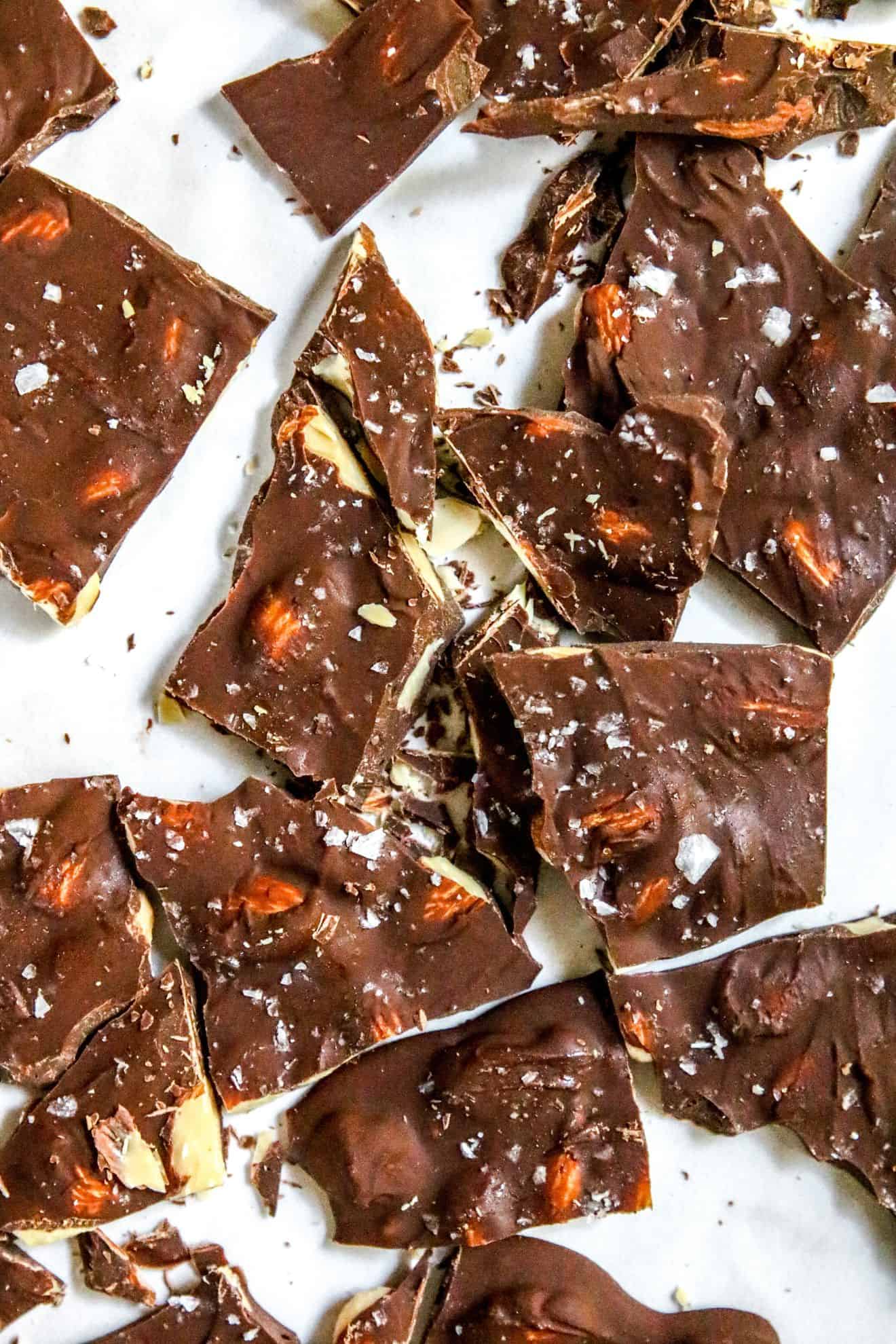 This is an overhead image of chocolate bark broken apart into pieces. The bark is sprinkled with flakey salt.
