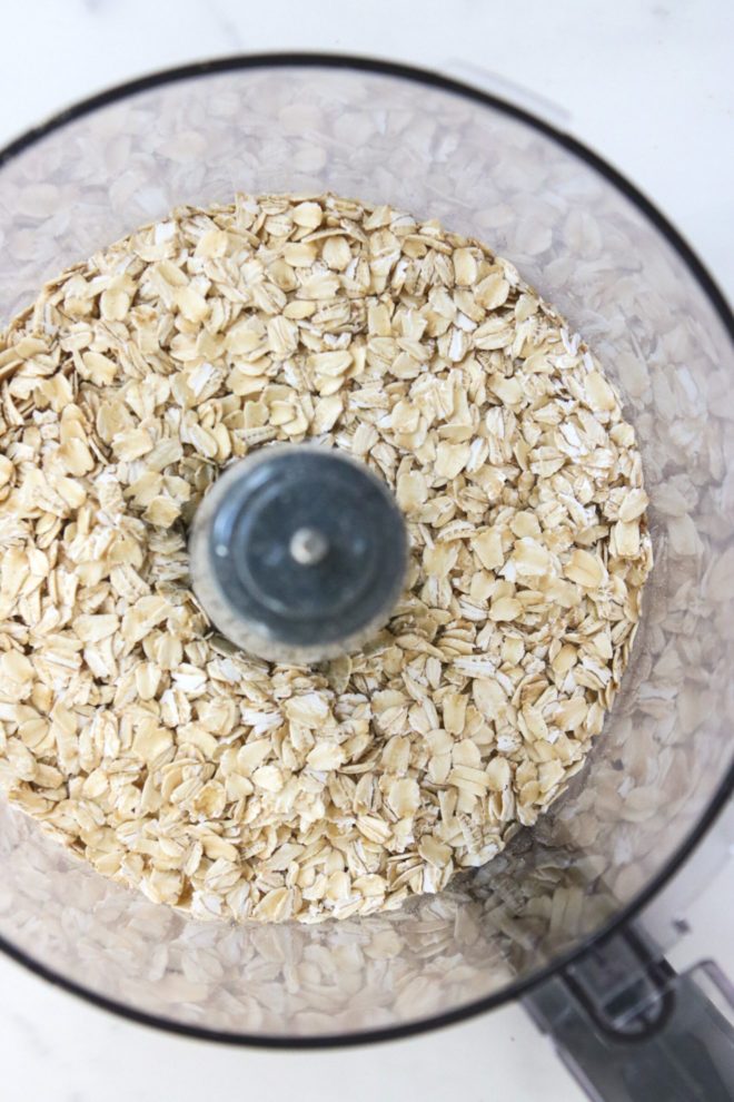 This is an overhead image of a food processor with oats in it. The food processor sits on a white counter.