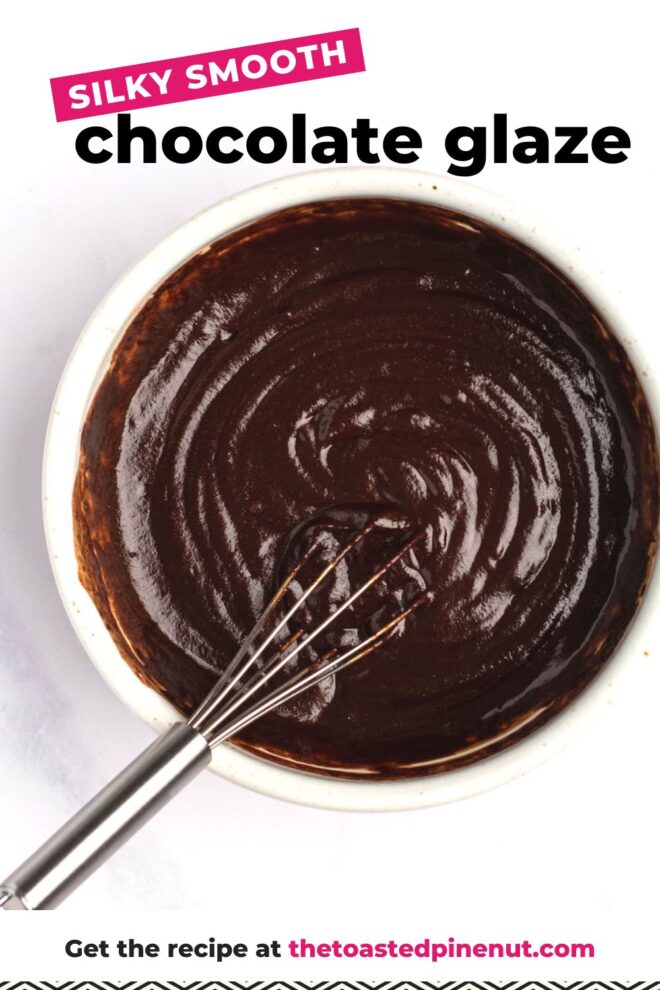 This is an overhead vertical image of a white bowl filled with chocolate glaze. A whisk is in the chocolate, leaning against the side of the bowl with the handle of the whisk to the bottom left corner of the image. The bowl sits on a light marble surface. Text overlay reads "silk smooth chocolate glaze get the recipe at thetoastedpinenut.com"