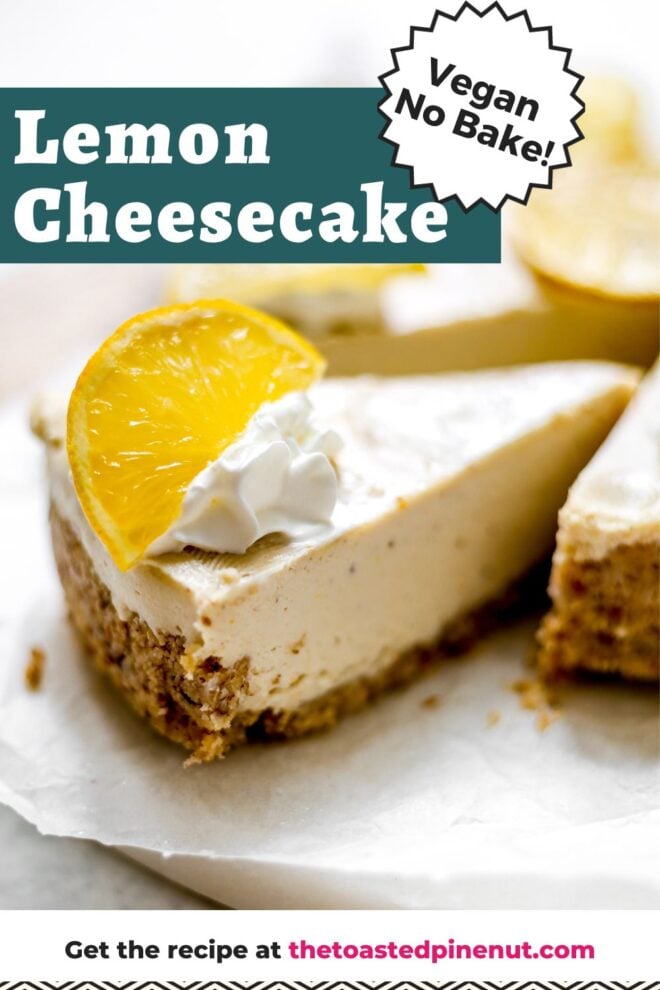 This is a vertical image looking at a no bake cheesecake from the side. The cheesecake is cut into and the image focuses on one slice pulled away from the rest of the cake. The slice has a nutty crust and creamy filling. The cheesecake is topped with dollops of whipped cream and wedges of lemon. The cheesecake sits on a white piece of parchment paper on a marble and wood circular cutting board on a white surface. Text overlay reads "lemon cheesecake vegan no bake!"