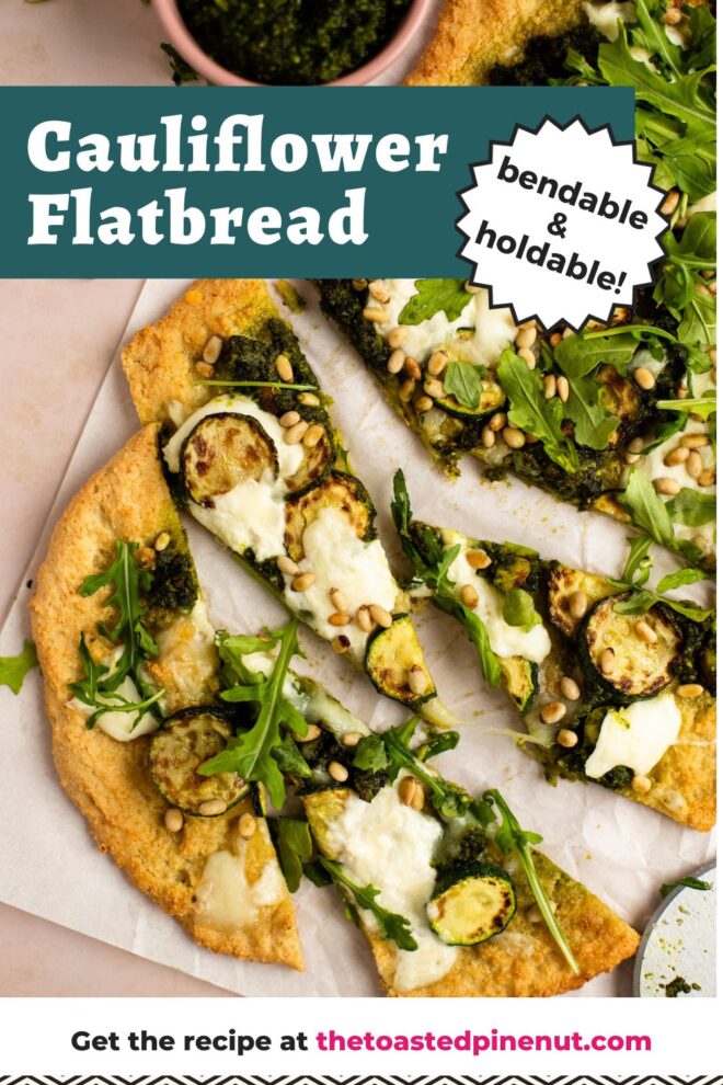 This is a vertical overhead image of a a few triangle slices of flatbread dolloped with pesto and shredded cheese, browned zucchini coins, burrata cheese, arugula and toasted pine nuts. The flatbread sits on a white piece of parchment paper on a light pink surface. Text overlay reads "cauliflower flatbread bendable & holdable"