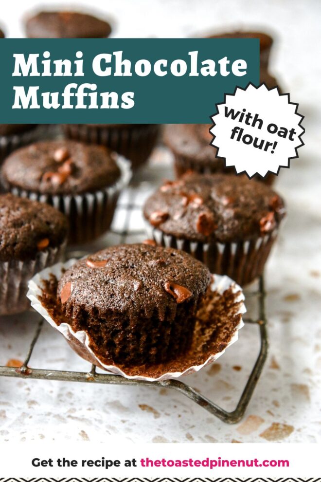 This is a vertical image looking at a cooling rack from the side. The cooling rack sits on a white terrazzo surface and has a lot of chocolate muffins on it. The center front muffin is in focus and the white parchment paper liner is pulled away from the sides of the mini muffin. Text overlay reads "mini chocolate muffins with oat flour."