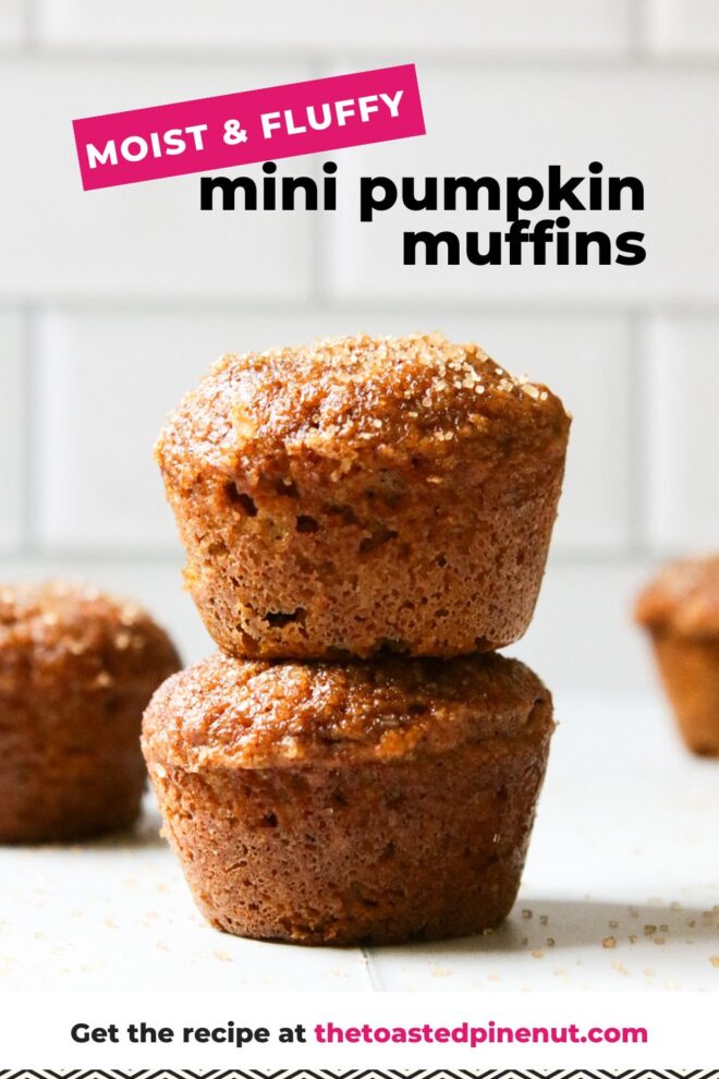 This is a vertical image looking at a stack of two mini muffins from the side. The stack sits on a white surface with more mini muffins blurred in the background. The top of the mini muffin has a brown sugar coating. In the far background are blurred white subway tiles. Text overlay reads "moist & fluffy mini pumpkin muffins."
