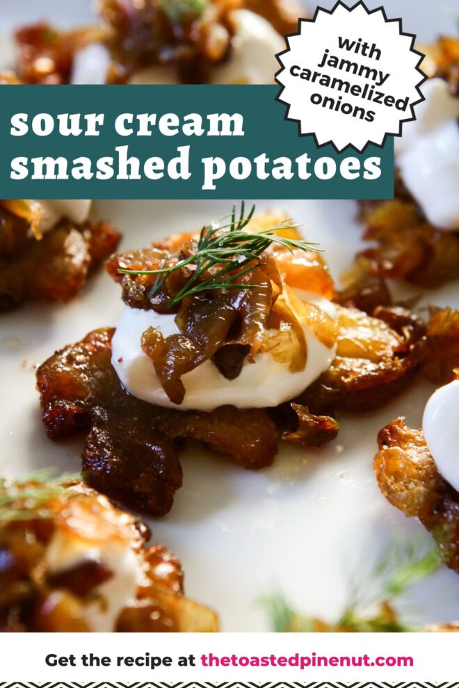 This is a vertical image focusing on a crispy roasted smashed potatoes on a white plate. The vantage point is from the side. The center potato is topped with sour cream, caramelized onions, and a small bit of fresh dill. More crispy potatoes with the same toppings are on the plate blurred around the center potato in focus. Text overlay reads "sour cream smashed potatoes with jammy caramelized onions" at the top and "get the recipe at thetoastedpinenut.com" at the bottom.