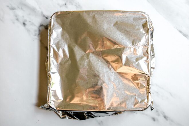 This is an overhead horizontal image looking down into a square metal pan covered with aluminum foil.